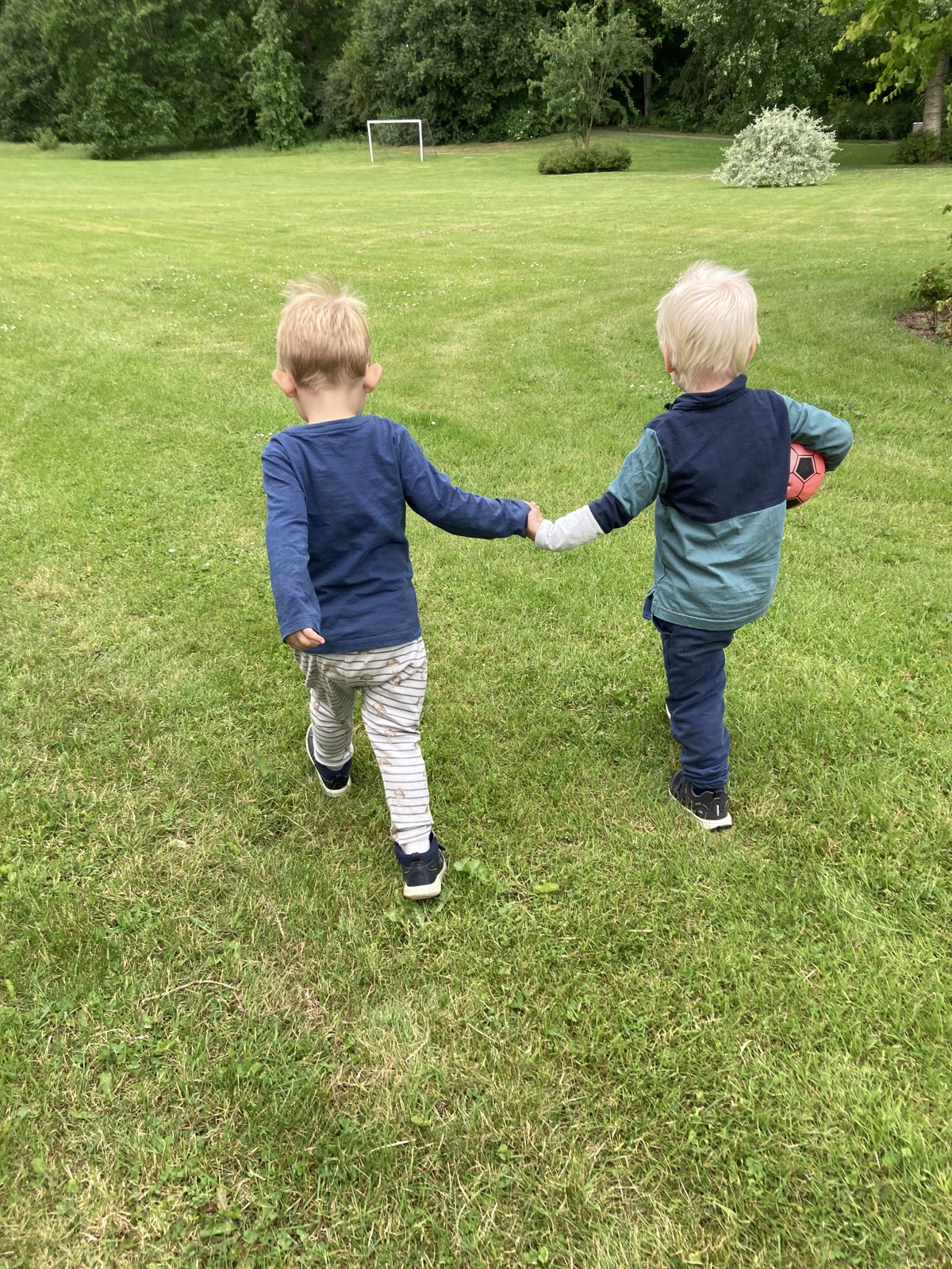 Drenge på tur med en fodbold under armen. De holder hinanden i hånd. 