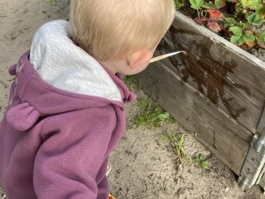 Der bliver malet med vand på højbedene ude på legepladsen